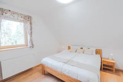 a white bedroom with a bed and a window at Rogla Alpina Residence in Zreče