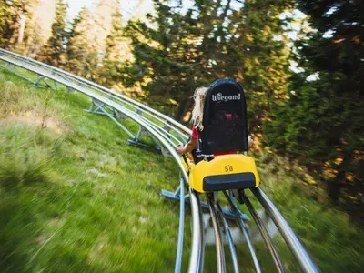 a girl is riding a train on a track at Rogla Alpina Residence in Zreče