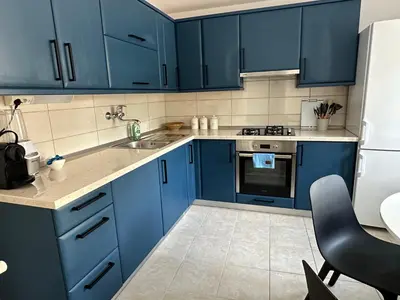a blue kitchen with blue cabinets and a sink at Alpine Echo Apartments in Bovec
