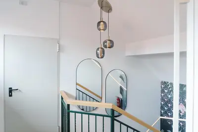 a hallway with two mirrors and a green railing at Lilija apartments in Trzin