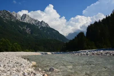 a river with rocks and mountains in the background at Rooms Barovc by the Lake Jasna in Kranjska Gora