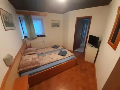 a small bedroom with a bed and a television at Rooms Barovc by the Lake Jasna in Kranjska Gora