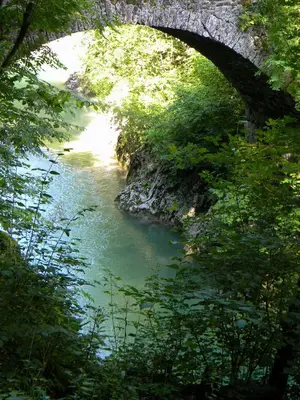 an old bridge over a river with green trees at Apartment Lošč - Podbela in Breginj