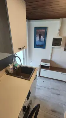 a kitchen with a sink and a counter with chairs at Počitniška hiška v gozdnem raju in Črni Vrh