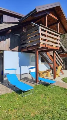 a house with blue chairs and a staircase at Počitniška hiška v gozdnem raju in Črni Vrh