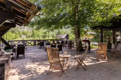 a patio with chairs and tables under a tree at Apartments Ukanc in Bohinj