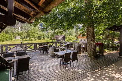 a wooden deck with tables and chairs under a tree at Apartments Ukanc in Bohinj