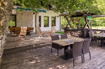 a wooden deck with tables and chairs and a grill at Apartments Ukanc in Bohinj