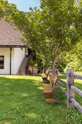 a fence with a wooden bench next to a tree at Apartments Ukanc in Bohinj