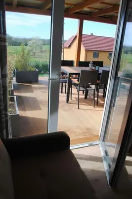 a sliding glass door of a patio with a table and chairs at Hiška Mirna ravnica in Moravske Toplice