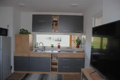 a kitchen with black cabinets and a sink and a window at Hiška Mirna ravnica in Moravske Toplice