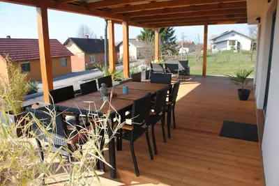 a wooden deck with a long table and chairs at Hiška Mirna ravnica in Moravske Toplice