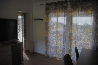 a living room with a curtain and a table with chairs at Hiška Mirna ravnica in Moravske Toplice