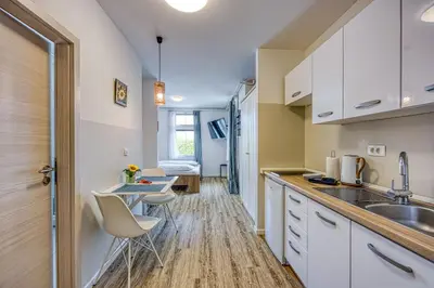 a kitchen with white cabinets and a sink and a table at Apartments Jantar in Novo Mesto