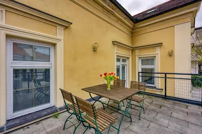 a wooden table with chairs and a vase of flowers on a balcony at Apartments Jantar in Novo Mesto