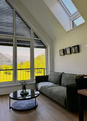 a living room with a couch and a table and windows at Alpine Haven in Bovec