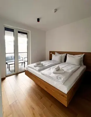 a bedroom with a bed with white sheets and a balcony at Alpine Haven in Bovec