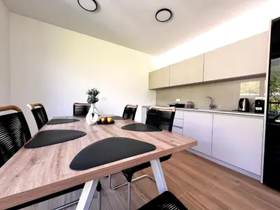 a dining room with a wooden table and a kitchen at Alpine Haven in Bovec