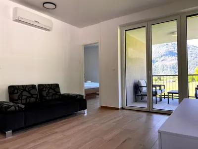 a living room with a black couch and a balcony at Alpine Haven in Bovec