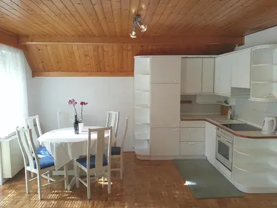 a kitchen with a table and chairs and a kitchen with white cabinets at Apartments Ana Kranjska Gora in Kranjska Gora