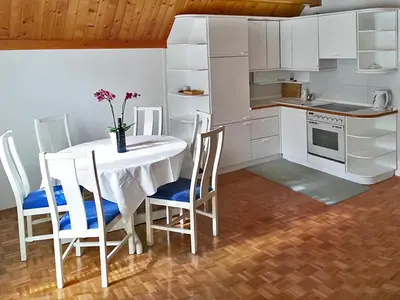 a kitchen with a white table and chairs and a kitchen with white cabinets at Apartments Ana Kranjska Gora in Kranjska Gora