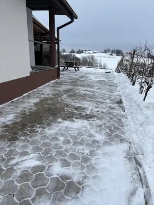 a snow covered sidewalk next to a building with a bench at APARTMA ENI in Moravske Toplice