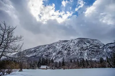 a mountain covered in snow with a house in the foreground at Holiday House Damjana (Hiška Damjana), Ukanc, Bohinjsko jezero in Bohinj