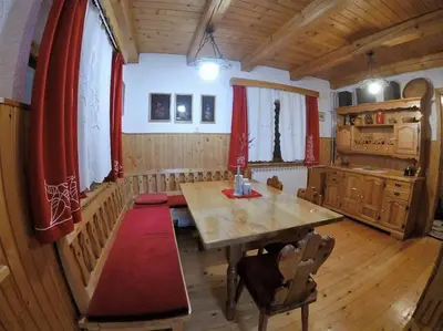 a dining room with a wooden table and red curtains at Holiday House Damjana (Hiška Damjana), Ukanc, Bohinjsko jezero in Bohinj