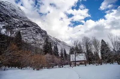 a snow covered mountain with a house in the foreground at Holiday House Damjana (Hiška Damjana), Ukanc, Bohinjsko jezero in Bohinj