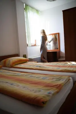 a woman sitting on a bed looking in a mirror at Apartments - Turistična kmetija Vrbnjak in Ljutomer