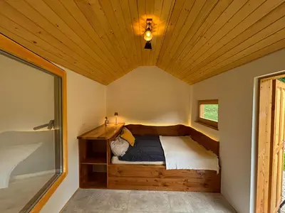 a bed in a room with a wooden ceiling at Na Logu - Farm Stay Ambrož Gregorc in Solčava