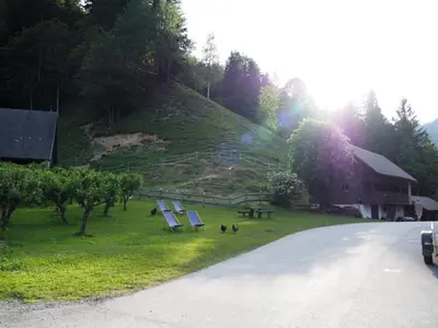 a group of lounge chairs in the grass next to a hill at Na Logu - Farm Stay Ambrož Gregorc in Solčava