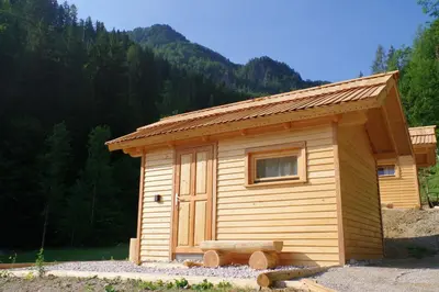 a small wooden cabin with a bench in front of it at Na Logu - Farm Stay Ambrož Gregorc in Solčava