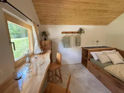 a bedroom with a bed and a desk and a window at Na Logu - Farm Stay Ambrož Gregorc in Solčava