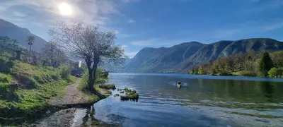 a person in a boat in a river with mountains at House Škantar Bohinj in Bohinj