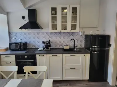 a kitchen with white cabinets and a black refrigerator at MK Studio in Maribor