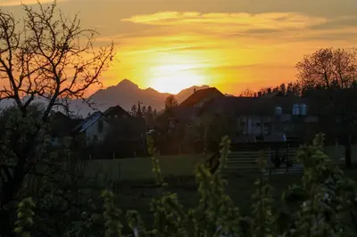 a sunset over a village with mountains in the background at Apartment Zupan in Preddvor