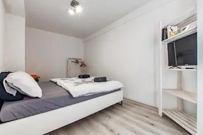 a white bedroom with a bed and a tv at Way to the Castle in Ljubljana