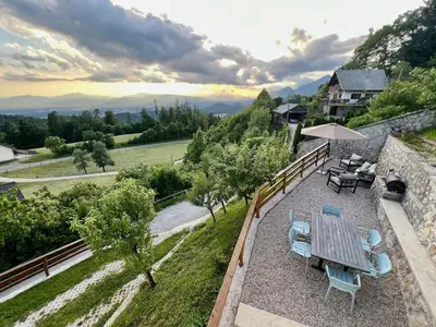 a patio with a table and chairs and an umbrella at Elipa Cottage in Cerklje na Gorenjskem
