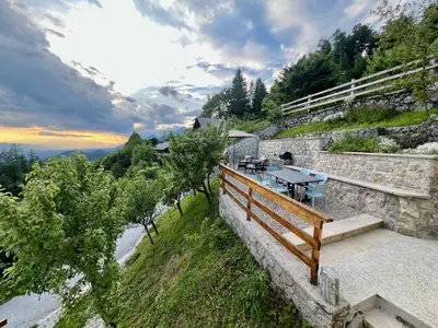 a patio with a table on the side of a mountain at Elipa Cottage in Cerklje na Gorenjskem