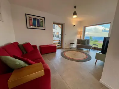 a living room with a red couch and a television at Elipa Cottage in Cerklje na Gorenjskem