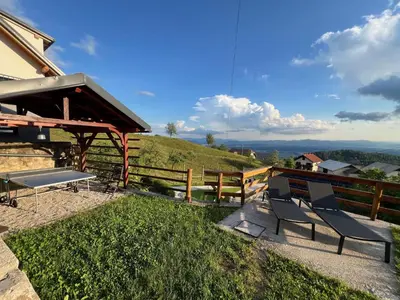 a patio with two chairs and a picnic table on a hill at Elipa Cottage in Cerklje na Gorenjskem