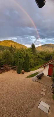 a rainbow in the sky over a yard with a house at Babičina hišica in Mišji Dol