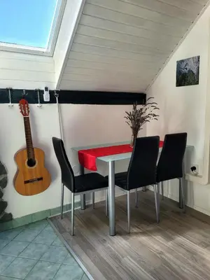 a table and chairs in a room with a guitar at Babičina hišica in Mišji Dol