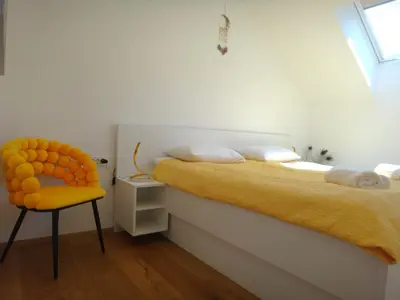 a bedroom with two beds and a yellow chair at Apartment 14 Luna in Bovec