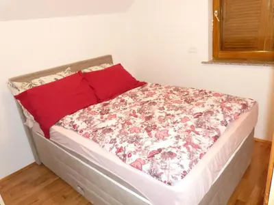 a bed in a room with a red pillow at Vineyard cottage Mavrica in Dragatuš