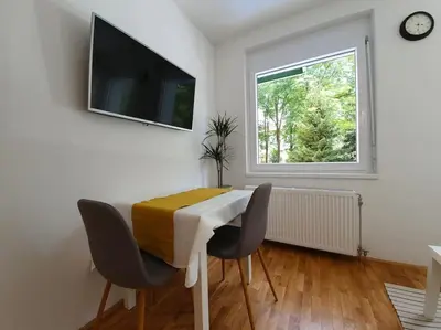 a dining room with a table and chairs and a window at Happy Vibes apartment, charming & with free parking in Ljubljana
