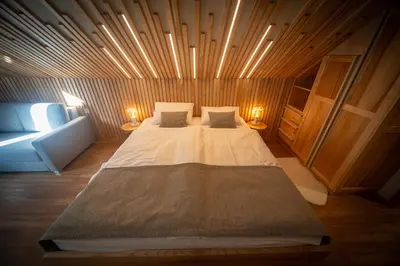 a large bed in a wooden room with two lamps at Turizem na kmetiji Rdečnik in Slovenj Gradec