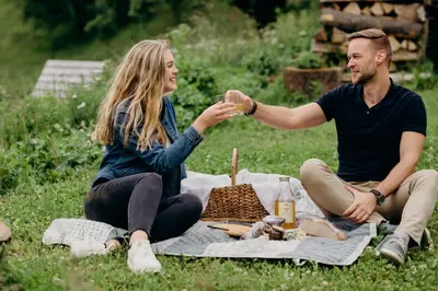 a man and woman sitting on the grass with a picnic at Turizem na kmetiji Rdečnik in Slovenj Gradec