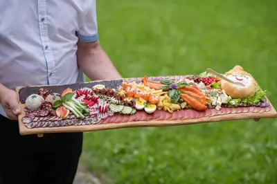 a person holding a tray of vegetables on a board at Turizem na kmetiji Rdečnik in Slovenj Gradec